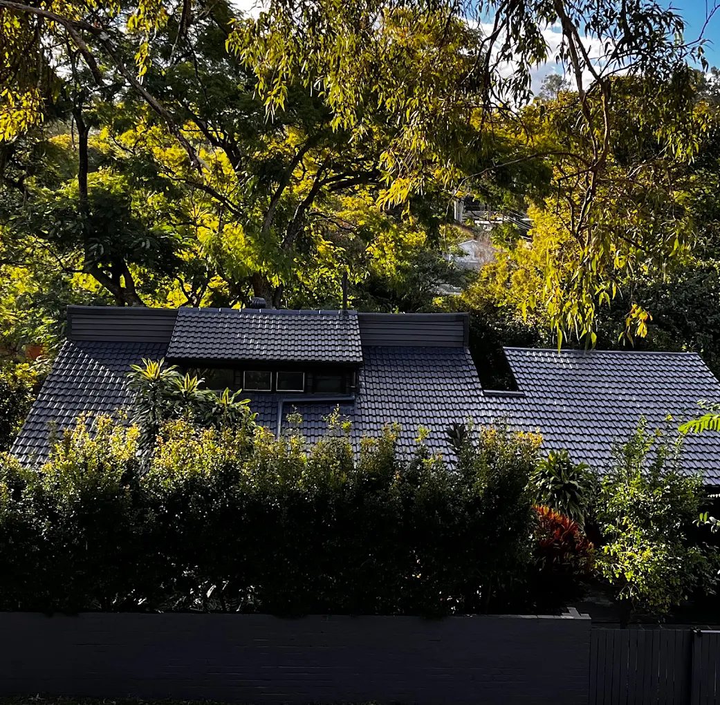 Finished charcoal roof restoration surrounded by trees